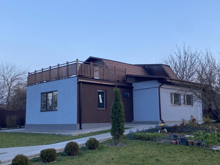 каркасная пристройка с террасой и деревянными декоративными перилами, с отделкой тёмно-коричневой и лазурной декоративной штукатуркой